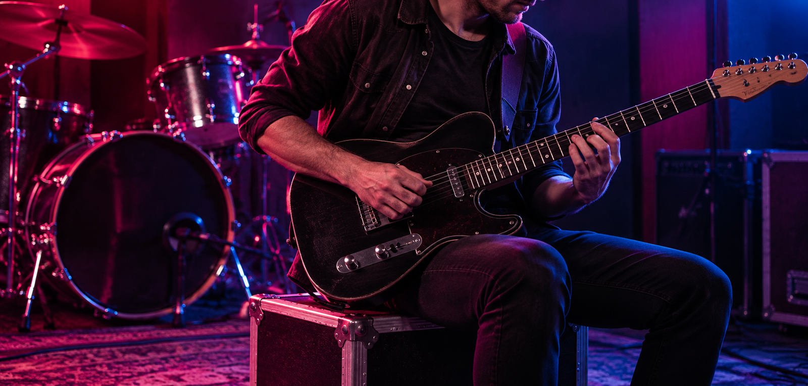 Guitarrista tocando no palco com bateria ao fundo